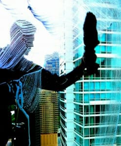 Photo shows a young man high up on the side of a Streeterville Chicago apartment building washing the windows - the photo was taken from inside the apartment looking out at his profile and shows a glass tower building in the background. Living In Streeterville - Life In Streeterville - Streeterville Living - Streeterville Condos For Sale - Chicago Streeterville real estate